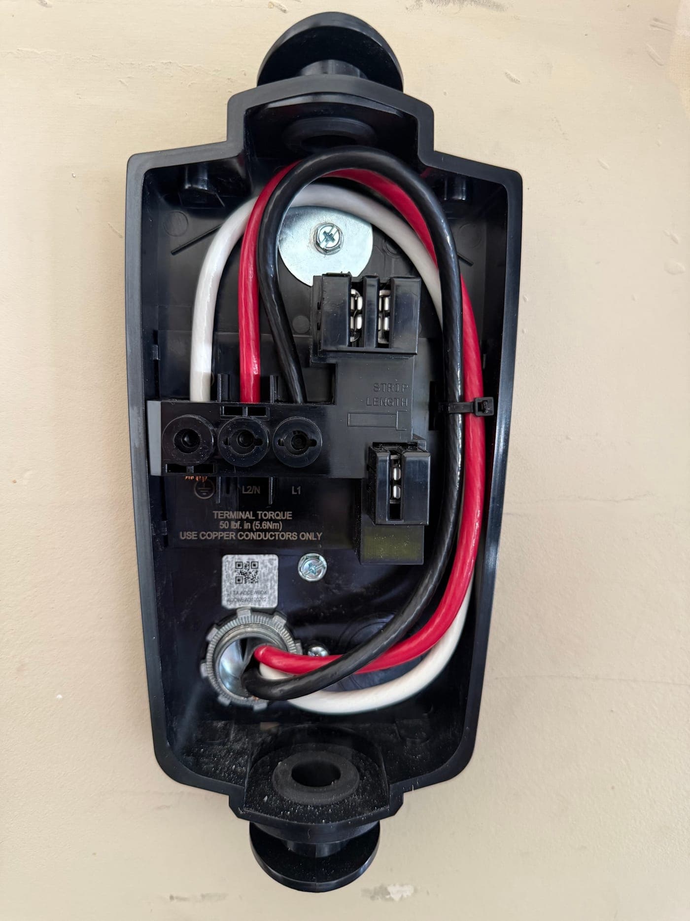 Inside a hardwired EV charger, showing the line and neutral conductors landed on their terminals