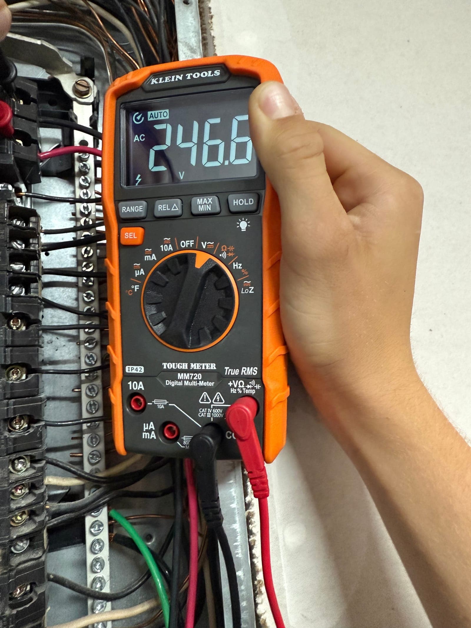 A multimeter reading 246 volts across the bus of an open residential load centre during an Armored Power Systems service call.